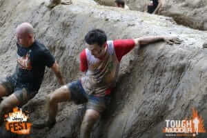 Charter Tax take part in Tough Mudder 2016: Two men climbing down a mud bank
